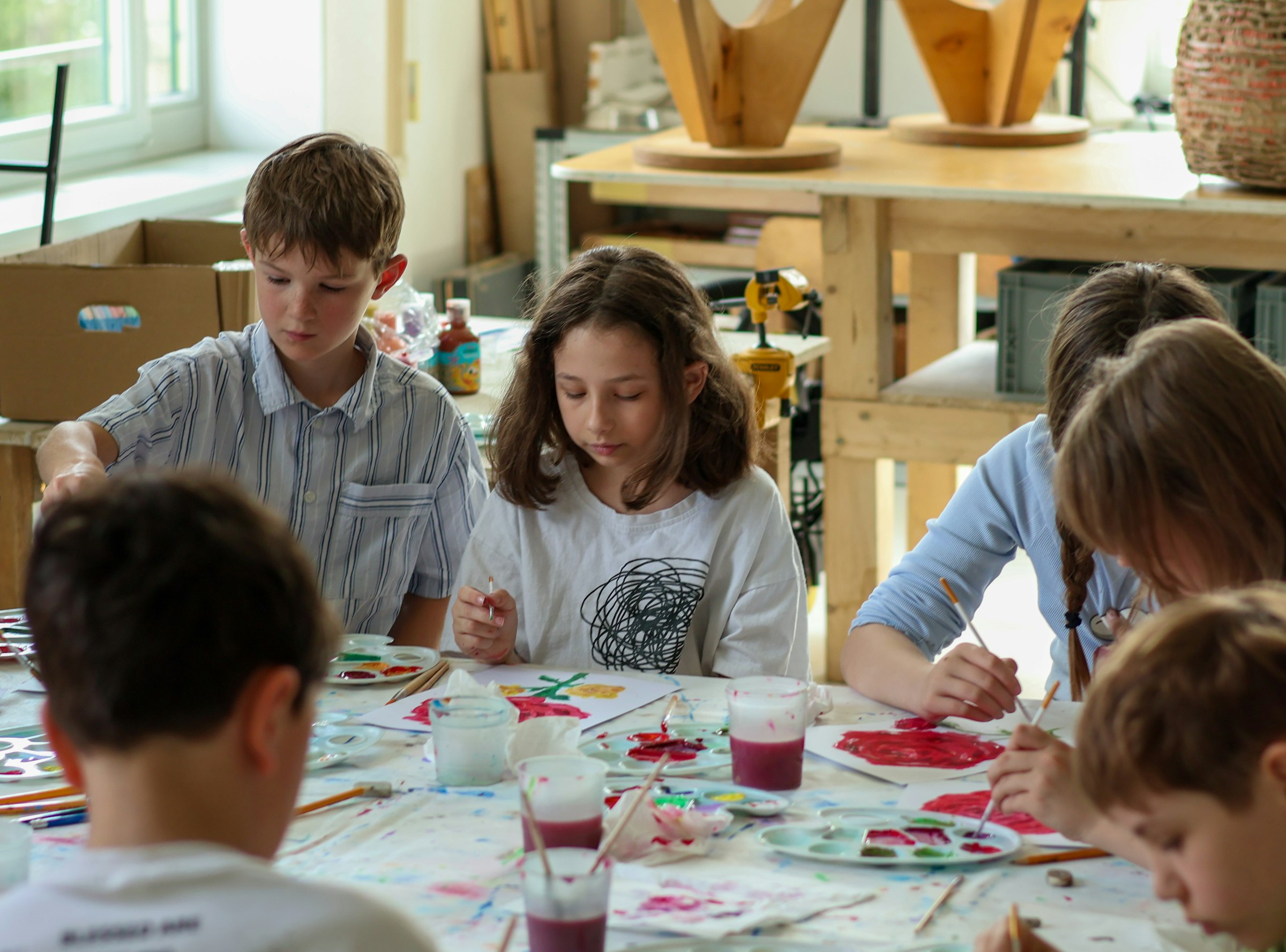 Children painting with watercolours together in a classroom